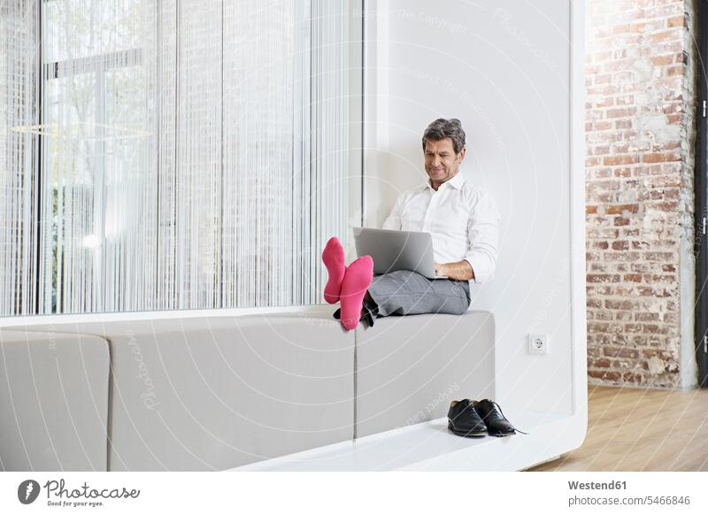 Geschäftsmann mit rosa Socken benutzt Laptop im Büro Notebook Laptops Notebooks Businessmann Businessmänner Geschäftsmänner Office Büros pink pinkfarben Strumpf