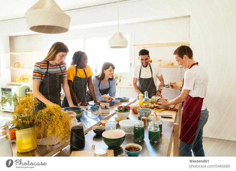 Freunde und Ausbilder in einem Koch-Workshop bei der Zubereitung von Essen kochen Ausbilderin Köchin Koechin Köchinnen Koechinnen Küche Kurs zubereiten