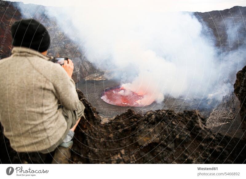 Afrika, Demokratische Republik Kongo, Virunga-Nationalpark, Mann sitzt über dem Krater des Vulkans Nyiragongo Europäer Kaukasier Europäisch kaukasisch Gefahr