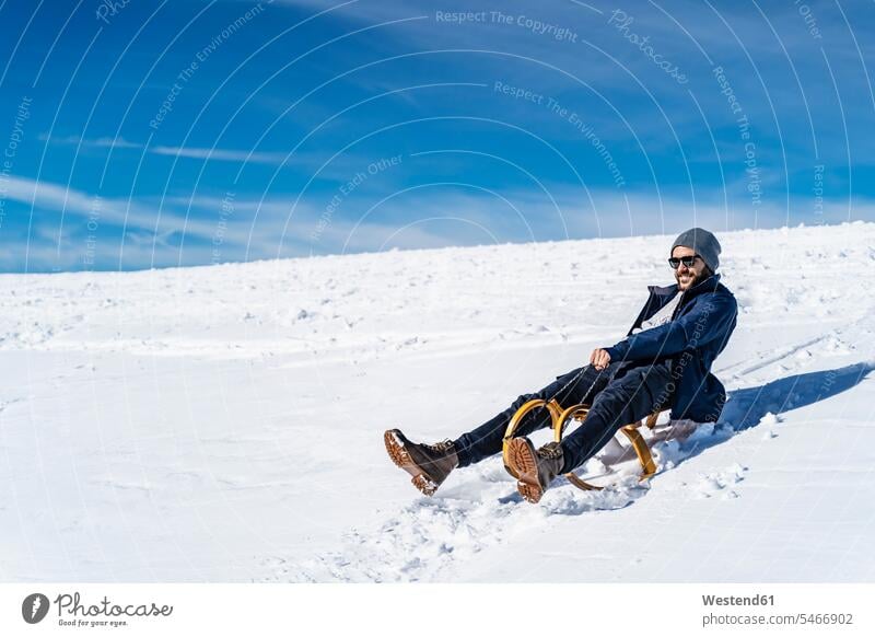 Deutschland, Bayern, Brauneck, Mann beim Schlittenfahren im Winter in den Bergen Rodelschlitten winterlich Winterzeit Männer männlich Berglandschaft