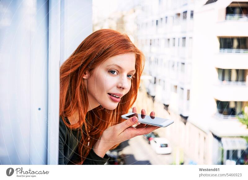 Porträt einer rothaarigen Frau am Telefon, die sich aus dem Fenster lehnt weiblich Frauen Portrait Porträts Portraits rote Haare rotes Haar rothaariger