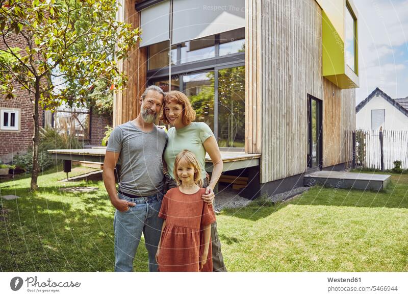 Lächelnde Tochter steht mit Eltern vor winzigem Haus im Hof Farbaufnahme Farbe Farbfoto Farbphoto Deutschland Freizeitbeschäftigung Muße Zeit Zeit haben