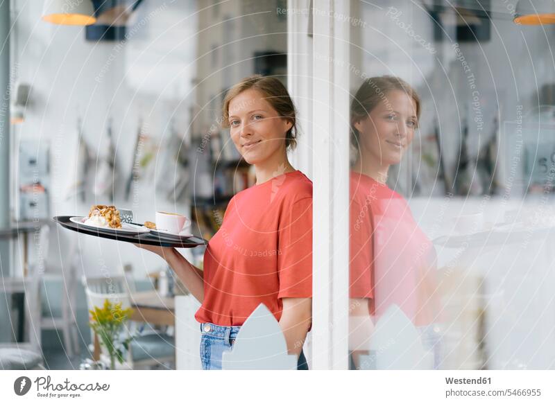 Porträt einer lächelnden jungen Frau, die Kaffee und Kuchen in einem Café serviert Cafe Kaffeehaus Bistro Cafes Cafés Kaffeehäuser Portrait Porträts Portraits