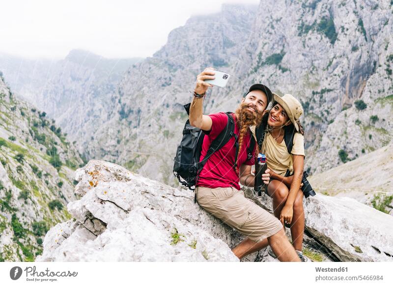Lächelndes Paar, das sich beim Sitzen auf einem Felsen in der Ruta Del Cares, Asturien, Spanien Farbaufnahme Farbe Farbfoto Farbphoto Außenaufnahme außen