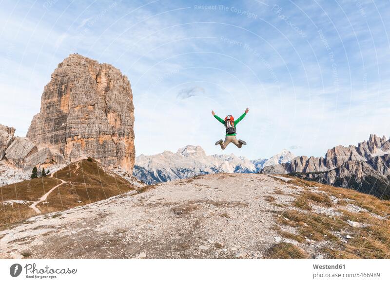 Italien, Cortina d'Ampezzo, glücklicher Wanderer beim Sprung auf den Berggipfel in den Dolomiten wandern Wanderung Mann Männer männlich Glück glücklich sein