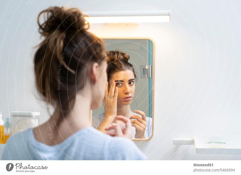 Rückansicht einer jungen Frau im Badezimmer früh Frühe Morgen daheim zu Hause alltäglich Schoenheit Schönheit Kosmetika Schoenheitspflege Schönheitspflege