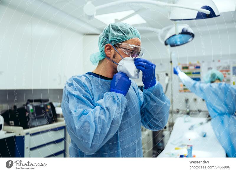 Arzt, der in der Notaufnahme eines Krankenhauses eine ffp2-Maske aufsetzt Job Berufe Berufstätigkeit Beschäftigung Jobs Brillen Arbeit Gesundheit