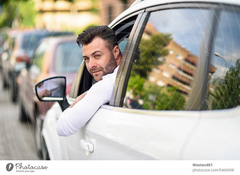 Mann lehnt sich in der Stadt aus dem Fenster seines Autos staedtisch städtisch Männer männlich Wagen PKWs Automobil Außenaufnahme draußen im Freien Erwachsener