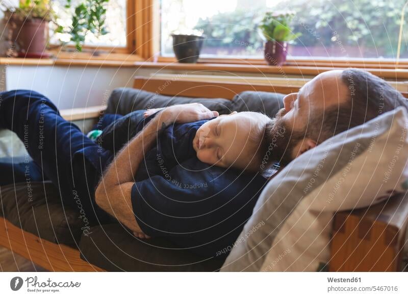 Vater und Sohn schlafen zusammen auf dem Sofa Polster Couch Couches Liege Sofas entspannen relaxen knuddeln schmusen schlafend Arm umlegen Umarmung Umarmungen