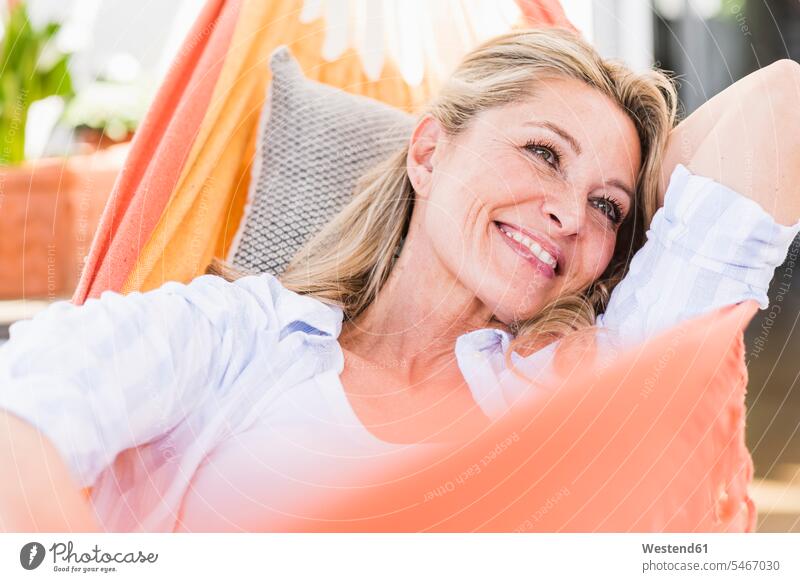 Porträt einer glücklichen reifen Frau, die sich in der Hängematte entspannt Polster Hängematten entspannen relaxen freuen Glück glücklich sein glücklichsein