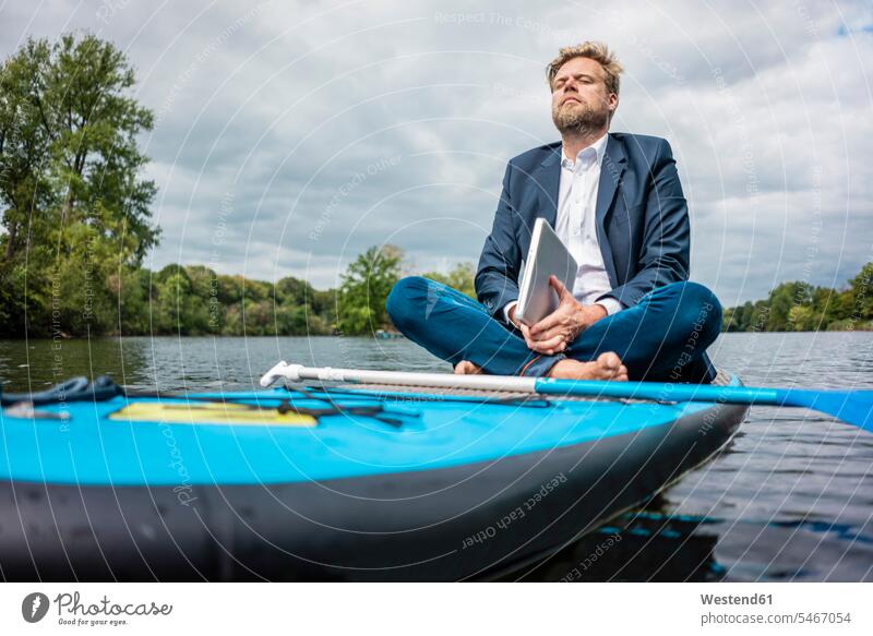Geschäftsmann mit Laptop sitzt auf einem SUP-Brett auf einem See geschäftlich Geschäftsleben Geschäftswelt Geschäftsperson Geschäftspersonen Businessmann