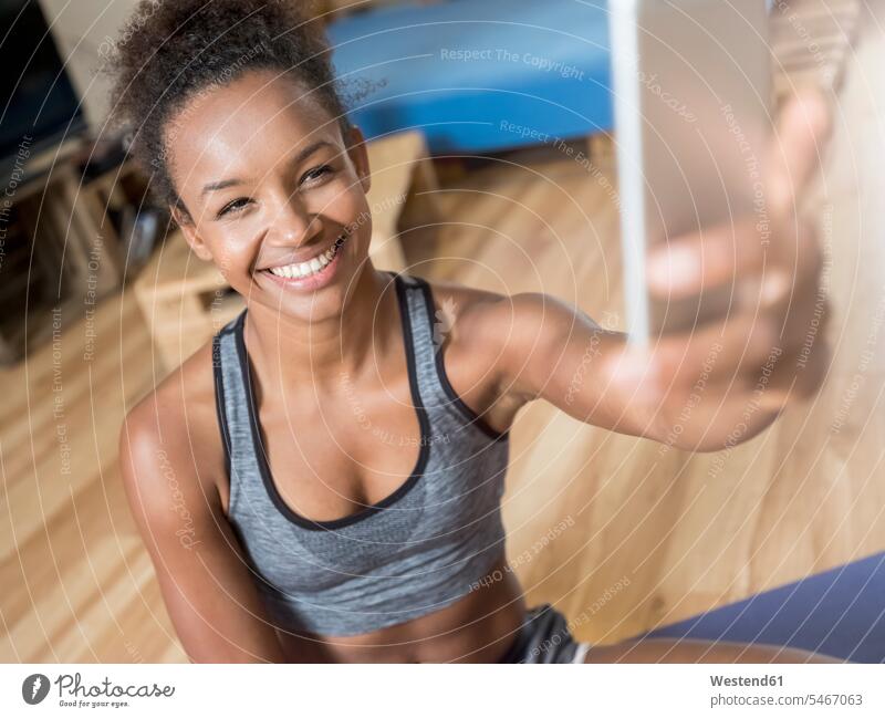 Lächelnde junge Frau in Sportkleidung macht ein Selfie Selfies lächeln Sportbekleidung Sportdress Kleidung weiblich Frauen Erwachsener erwachsen Mensch Menschen