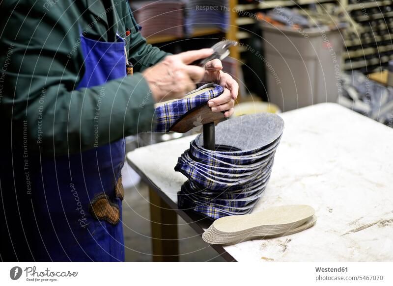 Nahaufnahme eines Schuhmachers, der in einer Werkstatt an Hausschuhen arbeitet Werkstätte Werkstaette Werkstaetten Werkstätten arbeiten Arbeit Schuster Puschen