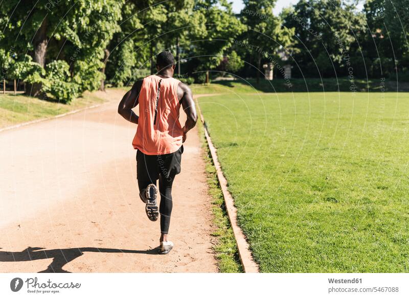 Junger Athlet beim Lauftraining auf dem Sportplatz Mann Männer männlich laufen rennen Ausdauer Ausdauernd fit trainieren Rückansicht Rueckansicht Rückenansicht