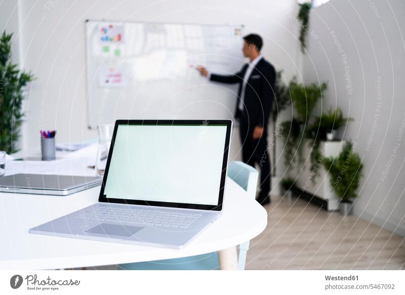 Laptop mit leerem Bildschirm auf dem Schreibtisch, während ein Geschäftsmann seine Strategie am Arbeitsplatz plant Farbaufnahme Farbe Farbfoto Farbphoto