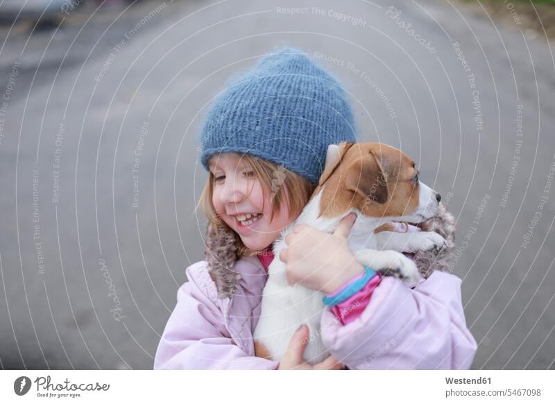 Glückliches kleines Mädchen mit Jack Russel Terrier-Welpe Hund Hunde Welfe Welfen Welpen halten glücklich glücklich sein glücklichsein weiblich Haustier