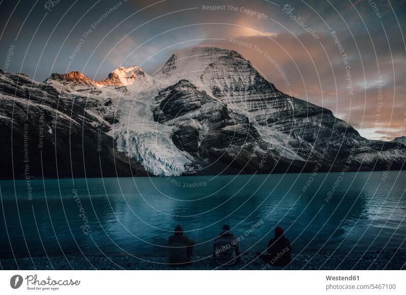 Kanada, Britisch-Kolumbien, Mount Robson Provincial Park, Wanderer, die in der Abenddämmerung am Berg Lake rasten sitzen sitzend sitzt ausruhen Rast Erholung