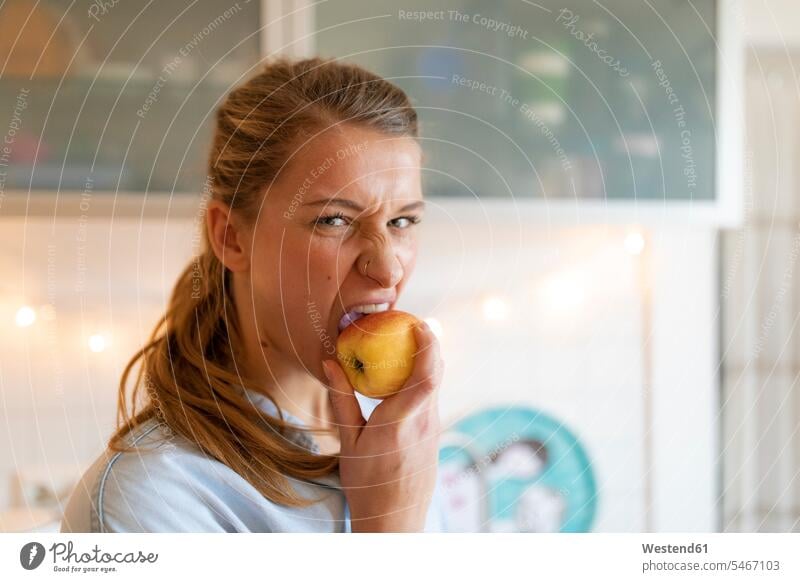 Porträt einer jungen Frau, die zu Hause einen Apfel isst Leute Menschen People Person Personen Alleinstehende Alleinstehender Singles Unverheiratete