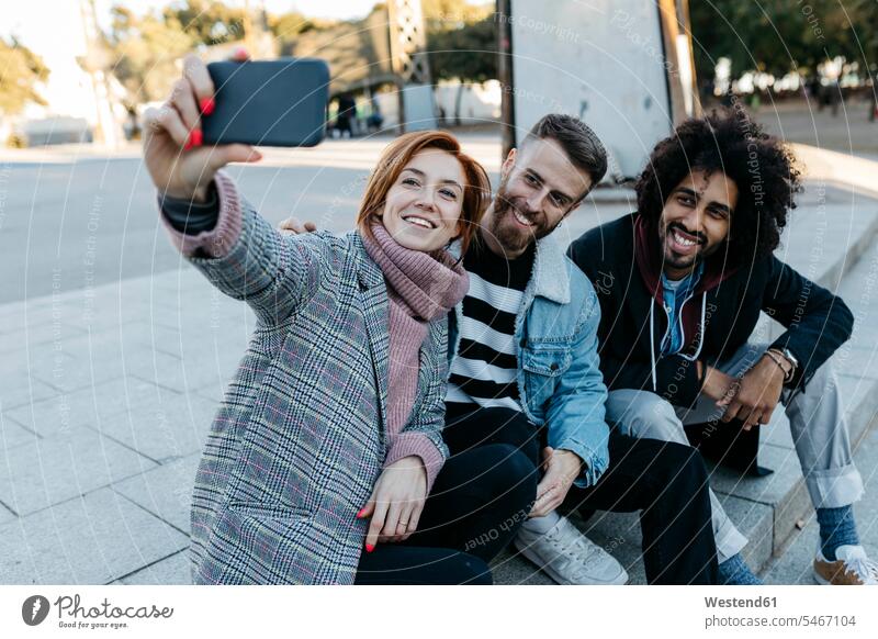 Drei glückliche Freunde sitzen im Freien und machen ein Selfie Selfies Glück glücklich sein glücklichsein Freundschaft Kameradschaft Barcelona Selbstportrait