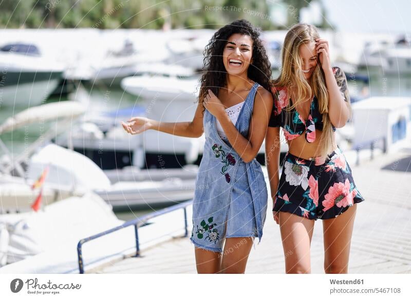 Zwei lachende junge Frauen an der Uferpromenade im Sommer Sommerzeit sommerlich Freundinnen Promenade Promenaden weiblich Freunde Freundschaft Kameradschaft