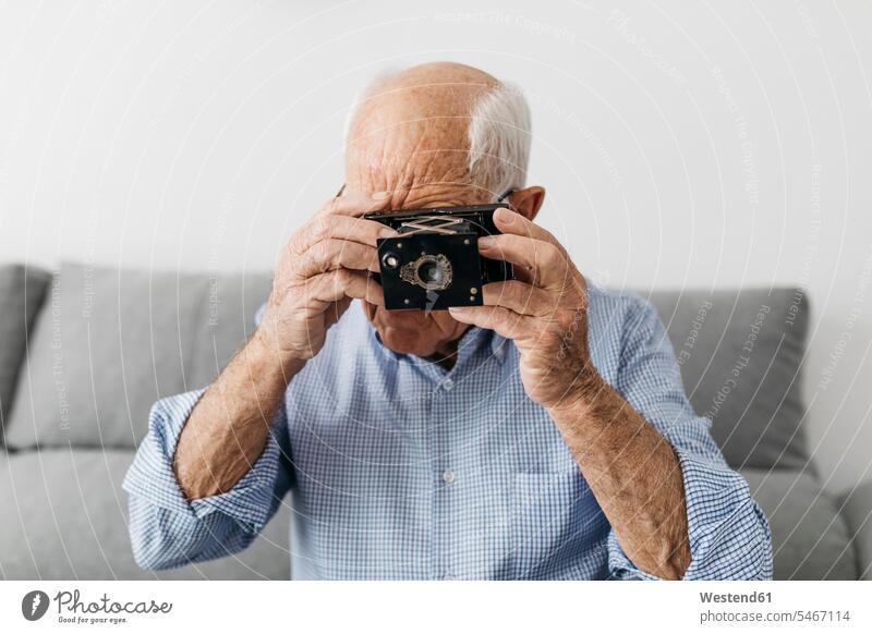 Älterer Mann macht ein Foto mit einer alten Fotokamera Kamera Kameras fotografieren Freizeit Muße Fotoapparat Hobby Hobbies Freizeitbeschäftigung
