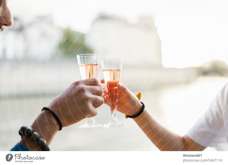 Nahaufnahme eines Paares, das am Flussufer Champagnergläser klimpert Sektflöte Champagnerflöte Sektglas anstoßen zuprosten anstossen Pärchen Partnerschaft