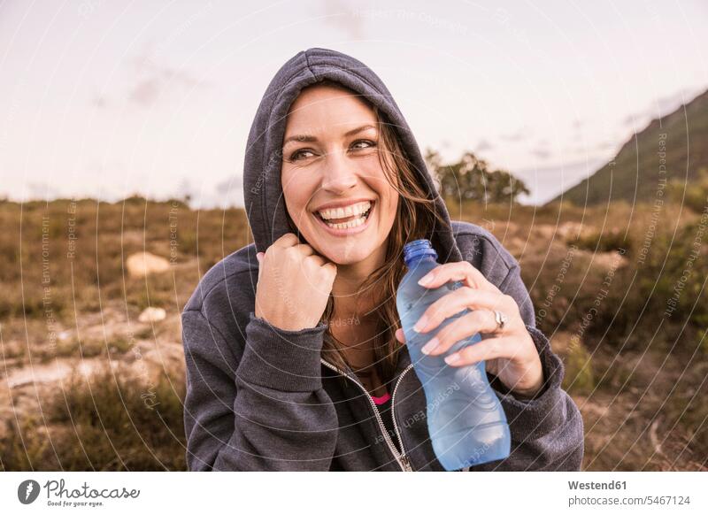 Glückliche Frau mit einer Flasche Wasser, die eine Pause vom Sport auf dem Land macht Europäer Europäisch Kaukasier kaukasisch eine Person ein Mensch