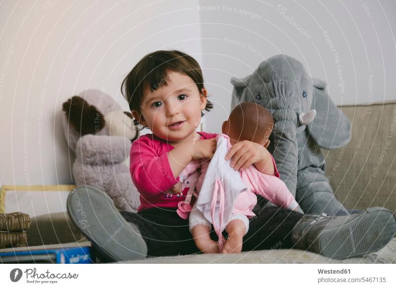 Porträt eines lächelnden Mädchens, das zu Hause mit einer Puppe spielt Portrait Porträts Portraits spielen weibliche Babys weibliches Baby weibliche Babies