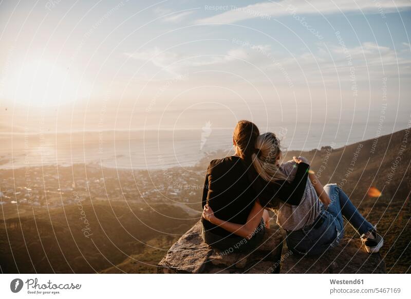 Südafrika, Kapstadt, Kloof Nek, zwei Frauen sitzen bei Sonnenuntergang auf einem Felsen Freundin sitzend sitzt Sonnenuntergänge weiblich Stimmung stimmungsvoll