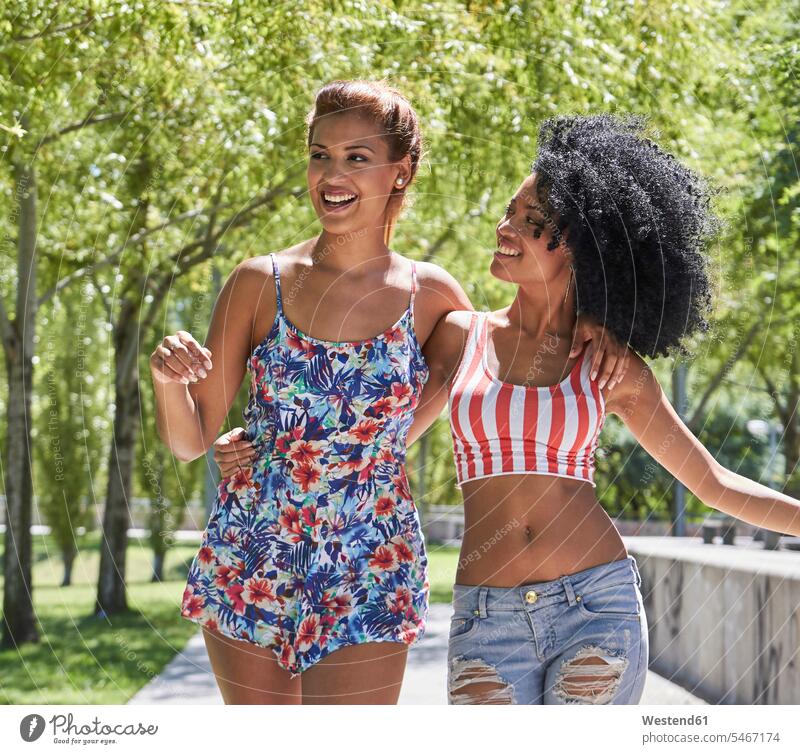 Freundinnen beim Spaziergang im Park Kleider Arm umlegen Umarmung Umarmungen sommerlich Sommerzeit freuen Frohsinn Fröhlichkeit Heiterkeit Glück glücklich sein