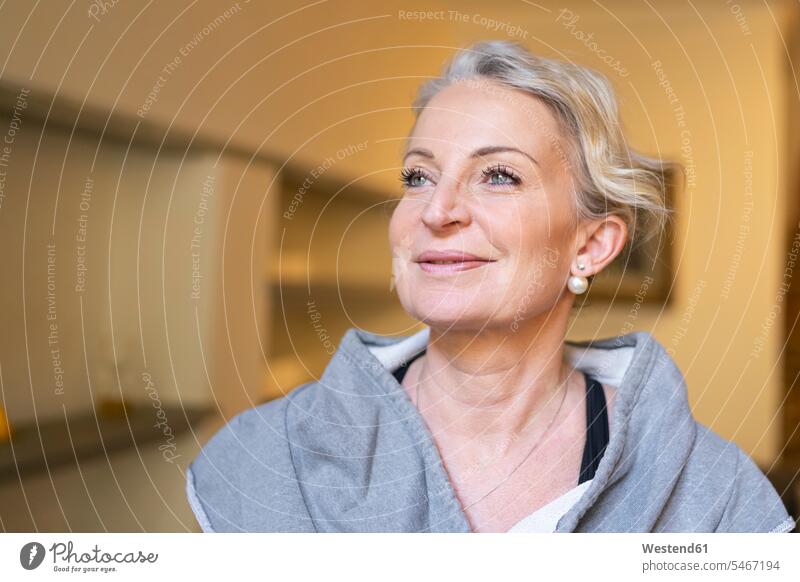 Porträt einer glücklichen reifen Frau im Wohnzimmer lächeln Ohrring Ohrringe Blick nach oben aufsehen Wimperntusche Mascara Best Ager bestes Alter