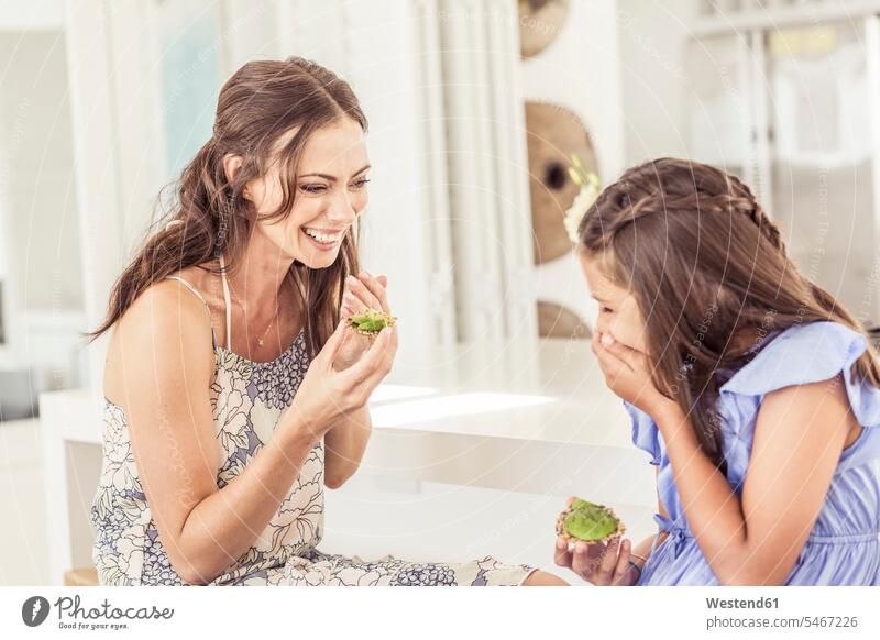 Glückliche Mutter und Tochter essen zu Hause Avocadobrot Kleider freuen Frohsinn Fröhlichkeit Heiterkeit geniessen Genuss glücklich sein glücklichsein