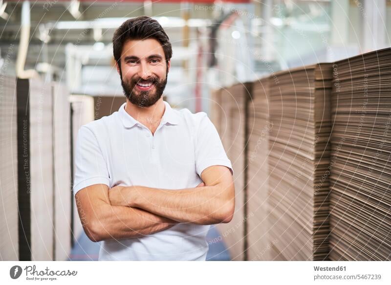 Porträt eines lächelnden Mannes in einer Fabrikhalle Job Berufe Berufstätigkeit Beschäftigung Jobs Arbeiter Kartons Pappkarton Pappkartons freuen Frohsinn