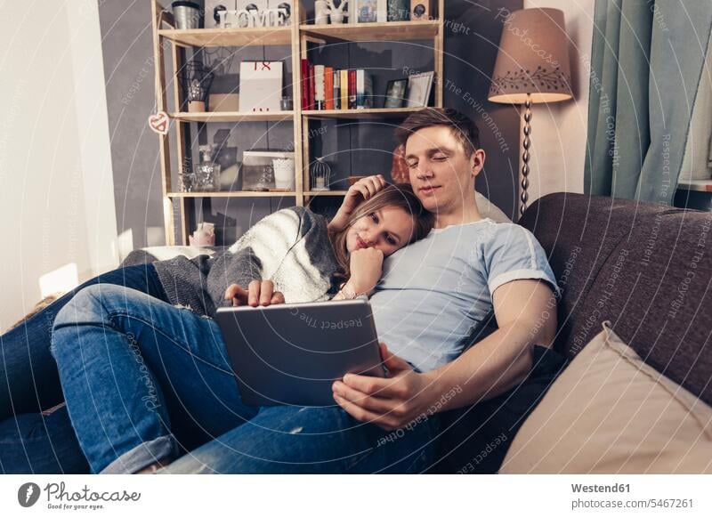Junges Paar mit Tablet auf der Couch zu Hause entspannt entspanntheit relaxt Pärchen Paare Partnerschaft Sofa Couches Liege Sofas Tablet Computer Tablet-PC