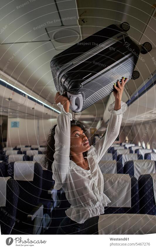 Junge Frau positioniert Gepäck im Gepäckraum eines Flugzeugs Tag Tageslichtaufnahme Tageslichtaufnahmen Tagesaufnahme am Tag Tagesaufnahmen tagsüber
