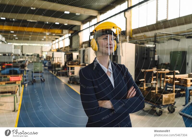 Porträt einer selbstbewussten Geschäftsfrau mit Schutzhelm und Ohrenschützern in einer Fabrik Leute Menschen People Person Personen Europäisch Kaukasier