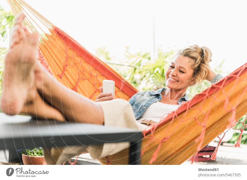 Porträt einer glücklichen reifen Frau Hängematten Tische Telekommunikation Handies Handys Mobiltelefon Mobiltelefone entspannen relaxen Lektüre freuen Glück