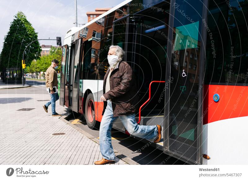 Älterer Mann mit Schutzmaske steigt aus öffentlichem Bus aus, Spanien Leute Menschen People Person Personen Europäisch Kaukasier kaukasisch 2 2 Menschen