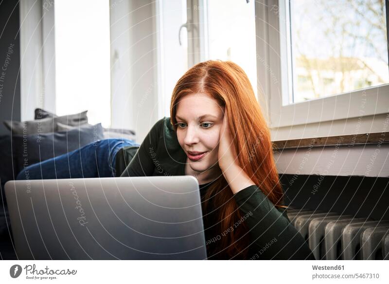 Porträt einer rothaarigen Frau, die zu Hause einen Laptop benutzt weiblich Frauen Zuhause daheim Notebook Laptops Notebooks benutzen benützen rote Haare