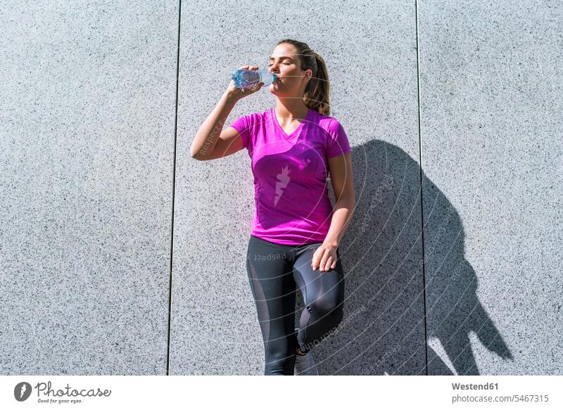 Junge Frau, die eine Pause vom Sport macht und aus der Flasche trinkt Flaschen weiblich Frauen trainieren trinken Erwachsener erwachsen Mensch Menschen Leute