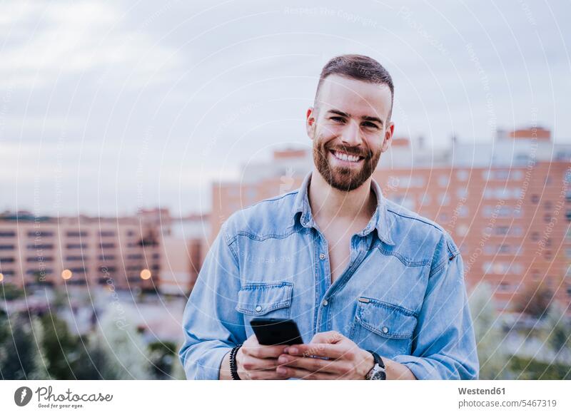 Porträt eines entspannten jungen Mannes mit Smartphone im Freien Leute Menschen People Person Personen Europäisch Kaukasier kaukasisch 1 Ein ein Mensch