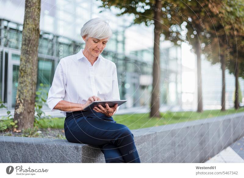 Ältere Geschäftsfrau sitzt draußen und benutzt ein Tablet Geschäftsfrauen Businesswomen Businessfrauen Businesswoman Frau weiblich Frauen Tablet Computer