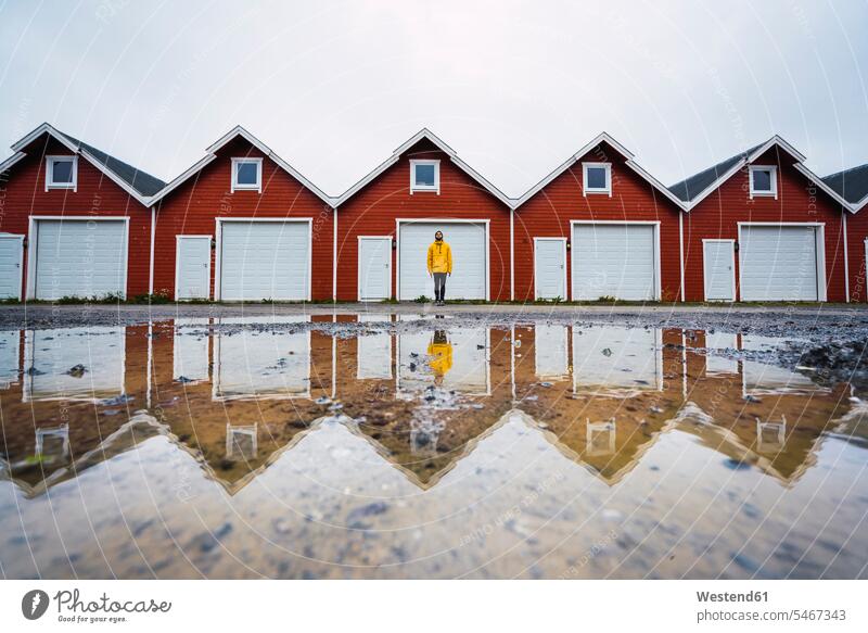 Norwegen, Mann steht vor einer Hüttenreihe Männer männlich stehen stehend Reihe aufgereiht in einer Reihe hintereinander nebeneinander Erwachsener erwachsen