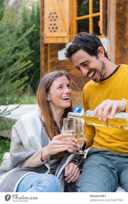 Glücklicher Mann schenkt Wein in ein Glas ein, das von seiner Freundin gehalten wird, während er im Freien sitzt Farbaufnahme Farbe Farbfoto Farbphoto Spanien