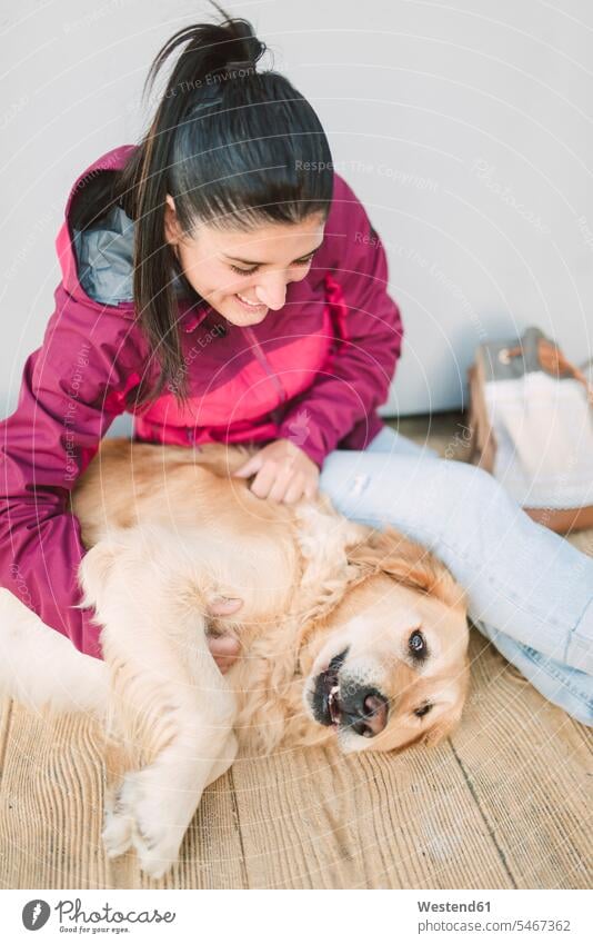 Glückliche junge Frau streichelt und spielt mit ihrem Golden Retriever Hund Hunde glücklich glücklich sein glücklichsein spielen weiblich Frauen streicheln