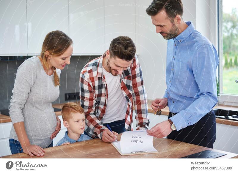 Familie mit Immobilienmakler unterzeichnet Vertrag in der Küche der neuen Wohnung Verträge Familien Makler unterschreiben Unterschrift unterzeichnen wohnen