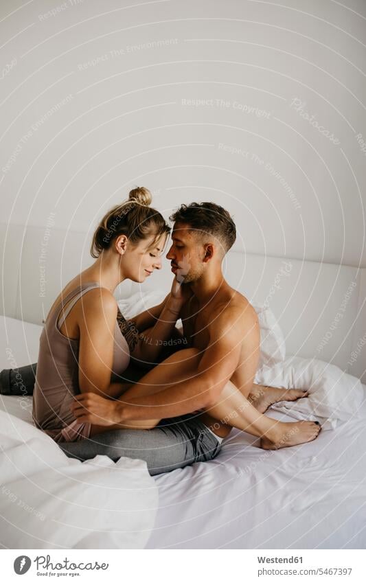 Romantisches junges Paar sitzt auf dem Bett romantisch schwärmerisch schwaermerisch gefuehlvoll gefühlvoll Romantik Betten sitzen sitzend Pärchen Paare