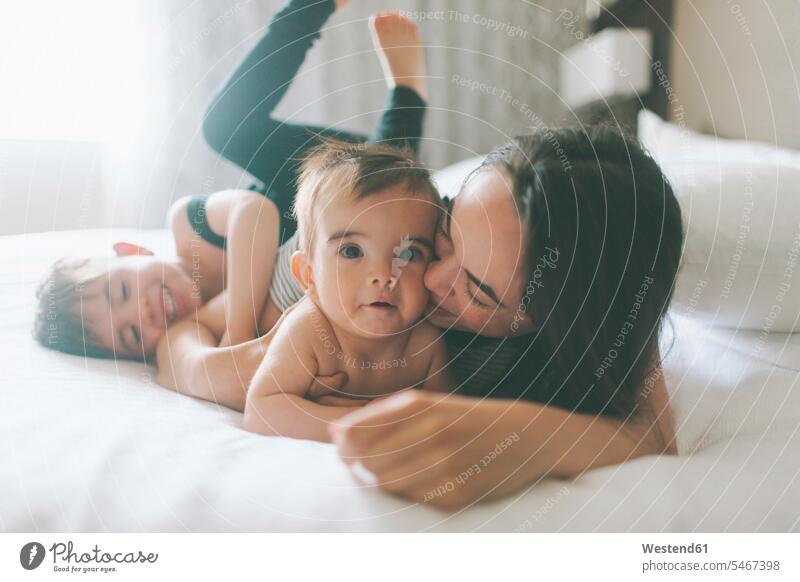 Mutter und zwei Jungen kuscheln im Bett zu Hause Betten knuddeln schmusen freuen behüten behütet geborgen Sicherheit geniessen Genuss Glück glücklich sein