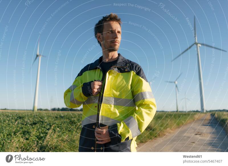 Porträt eines Ingenieurs auf einem Feldweg in einem Windpark Portrait Porträts Portraits Ingenieure Ingenieurwesen Anlagenbau Ingenieurwissenschaft Maschinenbau