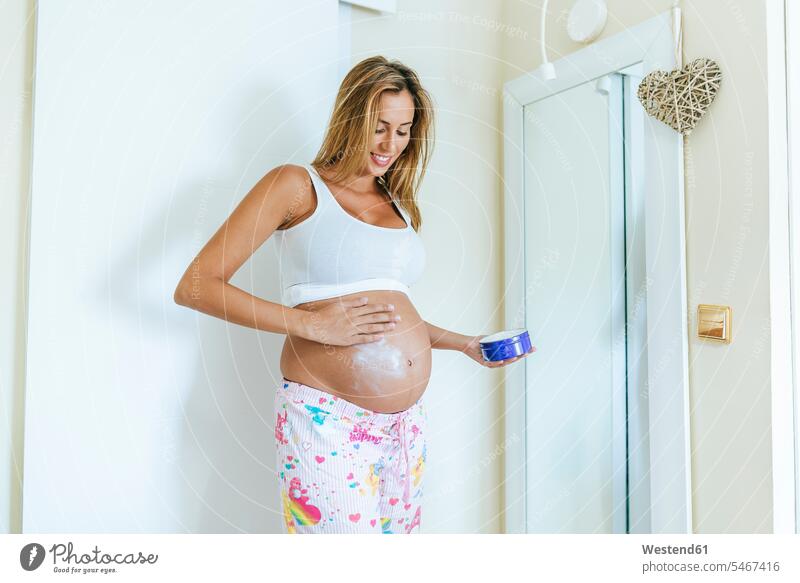 Schwangere Frau, die ihren Bauch eincremt anwenden auftragen Creme Cremes schwanger schwangere Frau weiblich Frauen Bäuche eincremen Erwachsener erwachsen
